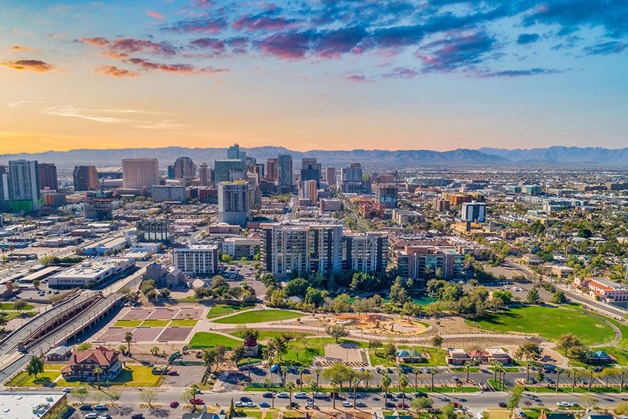 Contact - Aerial View of Phoenix, Arizona Displaying Many Buildings, Fields and Mountain Ranges in the Background at Sunset